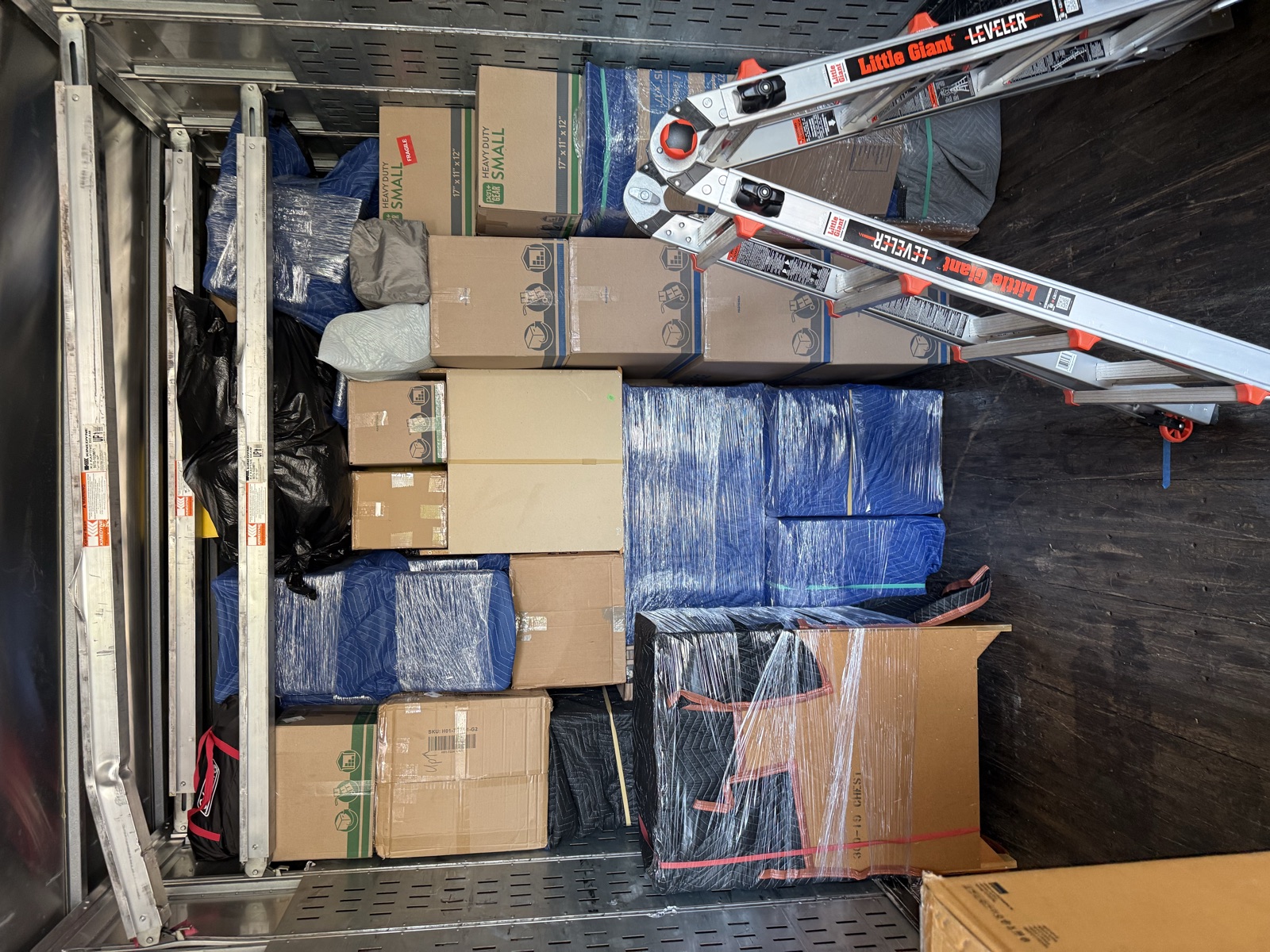 Moving labor crew loaded a rental truck with stacked boxes, blanket-wrapped furniture and a ladder across MD, DC and VA